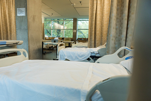 A photo of a large,  open plan hospital room with many beds ready for patients.