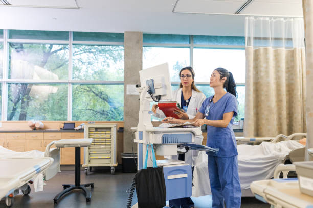 l’instructeur se tient près de son stagiaire pour montrer ses fonctions sur l’ordinateur - trainee computer medical student student photos et images de collection