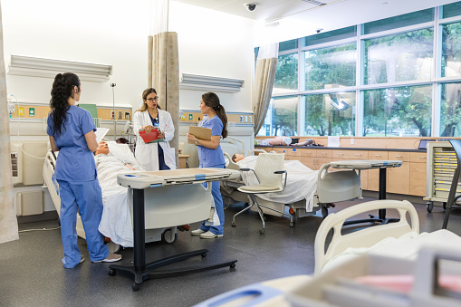 Female surgeon stands with the two medical students in the learning lab of the hospital