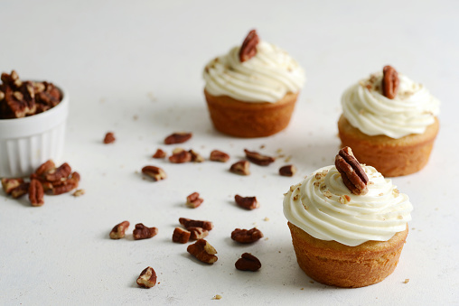 closeup butter pecan cupcakes with vanilla frosting and crushed nuts