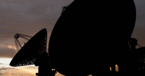 Satellite dish in a shadow against the sunset sky