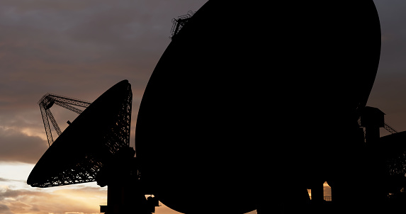 Satellite dish in a shadow against the sunset sky