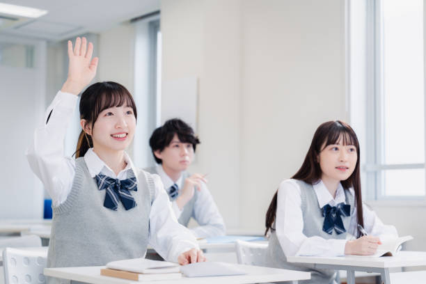 A high school girl raising her hand in class A high school girl raising her hand in class women satisfaction decisions cheerful stock pictures, royalty-free photos & images