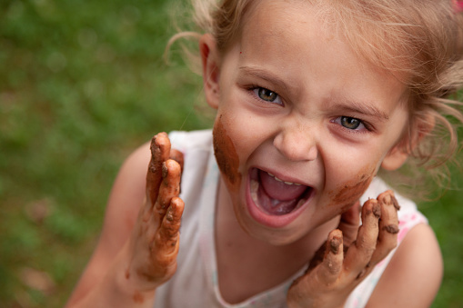 Close-up of a messy child with cheeks covered in clay