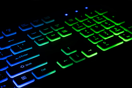 Fragment of the game keyboard with color backlight on black background. Close-up of computer keyboard. Selective focus.