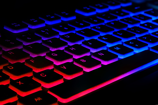 Fragment of the game keyboard with color backlight on black background. Close-up of computer keyboard. Selective focus.