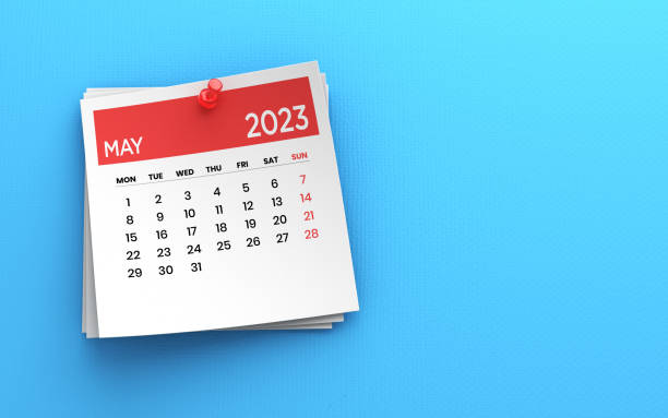 2023 年 5 月のカレンダーと青い紙の背景に赤いプッシュピンを投稿する写真 - may ストックフォトと画像