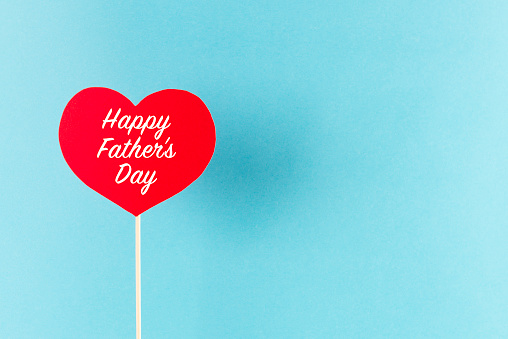 Happy Father’s Day written on red heart shape in front of blue background.