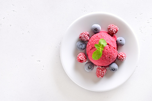 Raspberry sorbet on plate over white stone background with copy space. Top view, flat lay