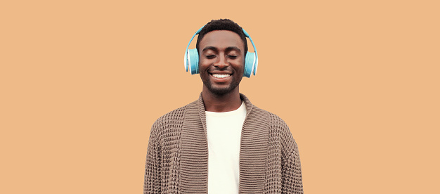 Young man using dating app on his smartphone while listening to music on wireless headphones