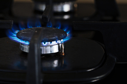 Close up of gas stove burning blue flame.