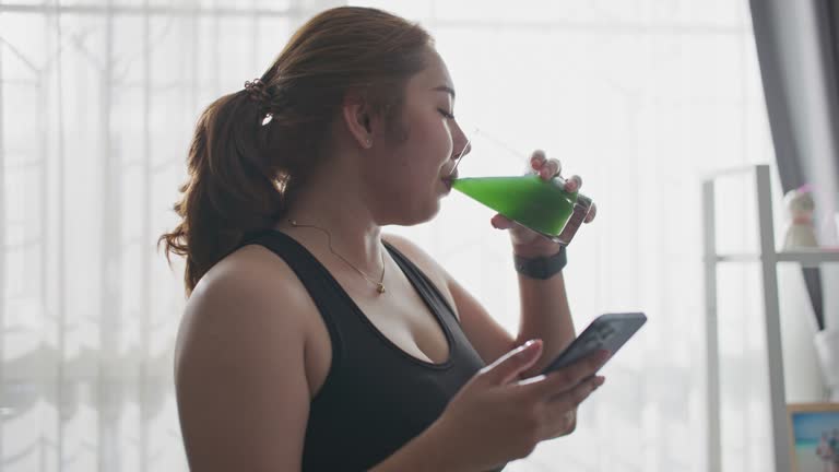 Overweight woman drinking green smoothie