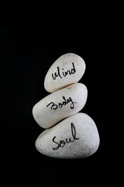 istock 3 white stones stacked, with mind body and soul hand written, 1463112314