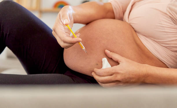 mujer embarazada irreconocible poniéndose una inyección en el vientre en casa. - diabetes insulin human fertility injecting fotografías e imágenes de stock