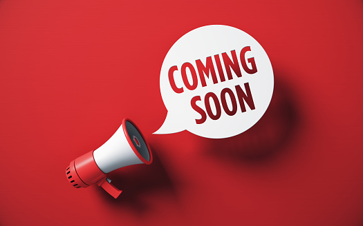 Coming Soon Written Speech Bubble and Red Megaphone on Red Background stock photo