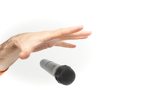 Caucasian male's hand dropping the mic, stretched hand and a microphone soft focus close up isolated on white background