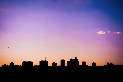 The silhouette of a cityscape against a beautiful blue-purple sky at dusk. The photo was taken during the transitional period between day and night, when the sky is filled with a mixture of blues, purples, and pinks.