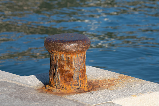 Harbor bollard for large naval vessels. The port wharf in central europe. Season of the summer.