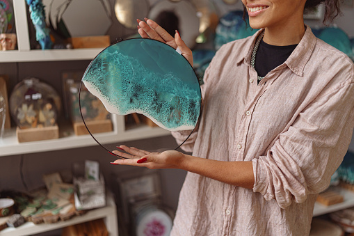 Woman decorator holding handmade epoxy resin glass tray with sea waves. High quality photo