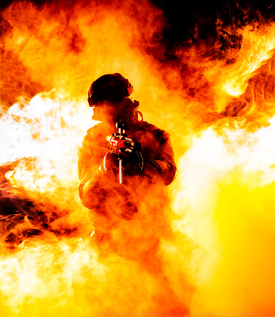 A silhouette of a soldier in fire and smoke, danger and intensity of battle. Dark outline in flames and billowing smoke, chaos and destruction of war. Respect for the sacrifices made by soldiers in defense of their country motherland.