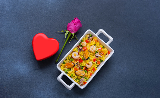 Paella with seafood on blue background. National Spanish and Valencian rice dish. Festive background concept for Valentine's Day. Close-up