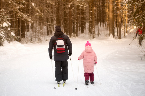 Syktyvkar, Komi, Russia, February 5, 2023,Father and daughter skiing in winter in the forest.Cross country ski.