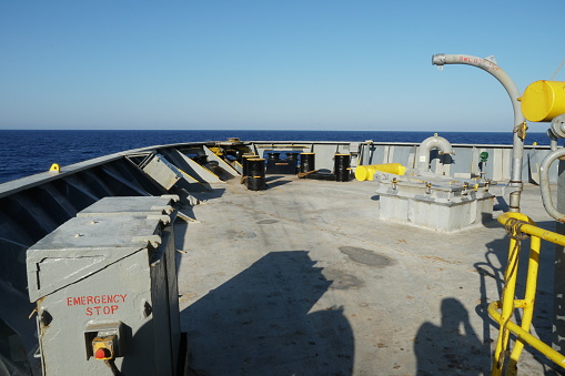 View on forward manoeuvring station on cargo container vessel with black and yellow painted bollards, mooring roller and column for remote control of mooring winch sailing through Mediterranean sea.