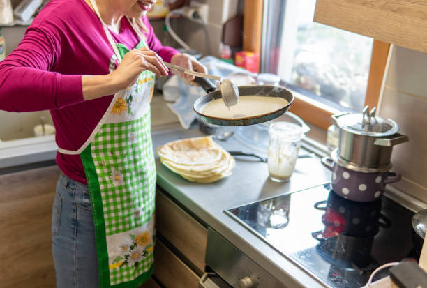 Mature woman making pancakes in the kitchen of her apartment