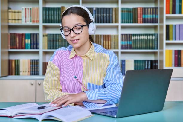 istock Teenage girl student studying in library, using laptop 1463138110