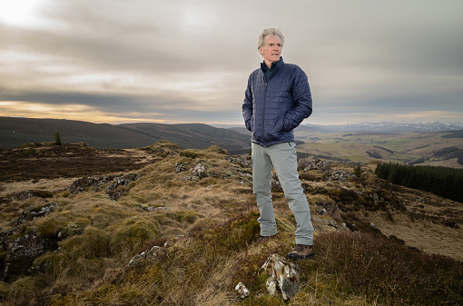 Retired male hiking on a hill in the Aberdeenshire region of Scotland.