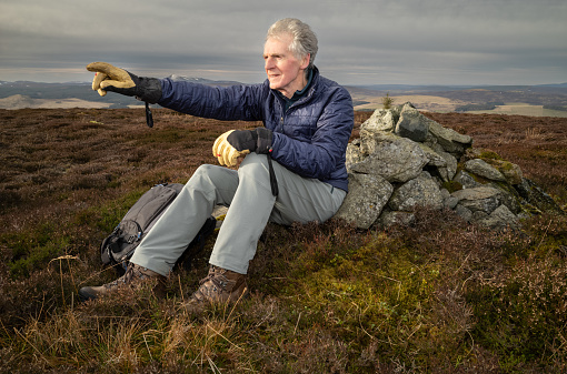 Retired male hiking on a hill in the Aberdeenshire region of Scotland.