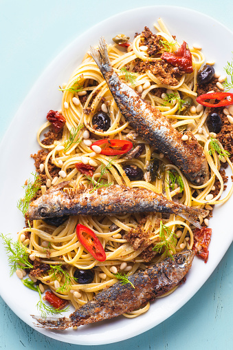 Pasta with sardines,  typical dish of the Sicilian culinary tradition, poor kitchen recipe, white wine with raisins, pine nuts, bread crumbs, olive oil and wild  fennel. La cucina povera, close-up