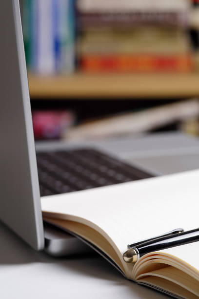 istock Close up of open notepad and  laptop computer at the library 1463142540