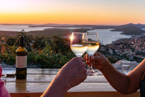 einen toast mit wein bei einem malerischen blick auf die kroatischen losinjer inseln in der kvarner bucht bei sonnenuntergang machen - croatian culture stock-fotos und bilder