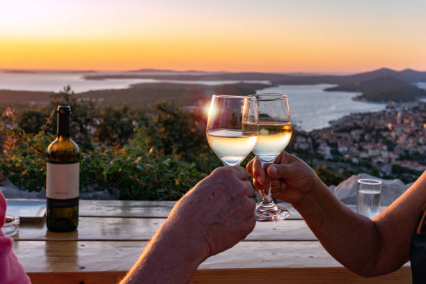 wznoszenie toastu winem nad malowniczym widokiem na chorwackie wyspy lošinj w zatoce kvarnerskiej o zachodzie słońca - chorwacja zdjęcia i obrazy z banku zdjęć