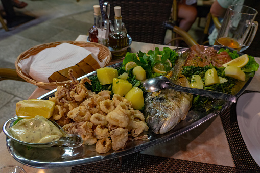 seafood fish platter in Croatia with tuna fish Calamari and spinat potato .