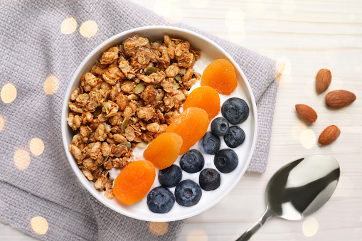 Delicious granola with fruits on white wooden table, flat lay