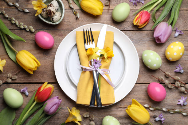 istock Festive Easter table setting with painted eggs and floral decor on wooden background, flat lay 1463163538