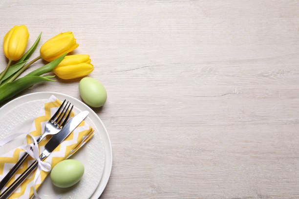 istock Festive Easter table setting with eggs and flowers on light wooden background, flat lay. Space for text 1463163556