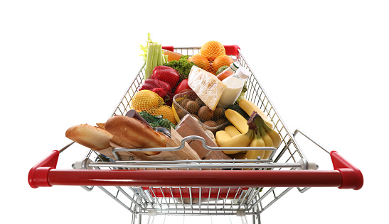 Shopping cart full of groceries on white background, above view