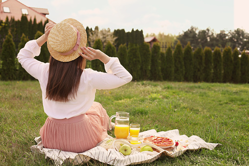 Young woman having picnic outdoors on summer day, back view