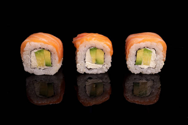 istock Row of sushi, rolls with salmon and avocado on a mirror black surface 1463175212