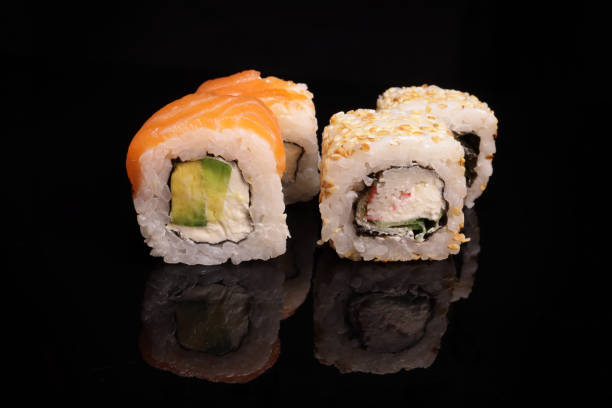 istock Various sushi with salmon, tuna, avocado, sesame on a mirror black surface 1463175434