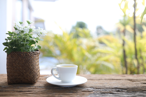 white tea cup and Verbena plant pot wooden table balcony