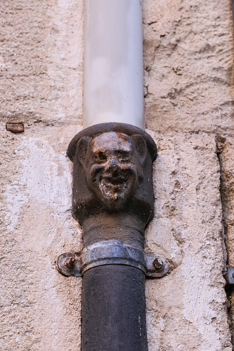 Face on old forged metal gutter in Alicante. Modernist style