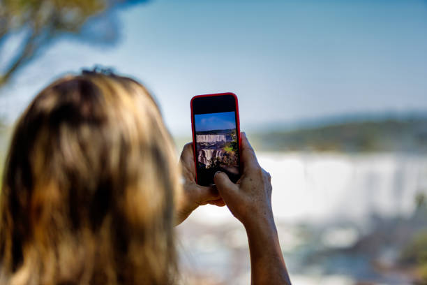 Woman takes a picture of the Iguazu Falls stock photo