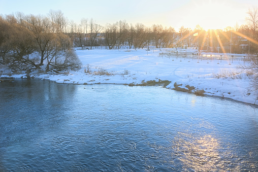 Winter view of the bank of the Moscow River in the city of Mozhaisk in the backlight of the sun. Beautiful view of the river banks in winter.