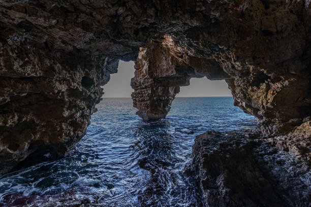 istock Sea waves crashing into a dark rock cave 1463183726