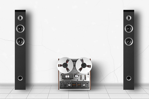 Home interior - Two front view tower loudspeaker enclosure and retro reel to reel tapes recorder of white wall background