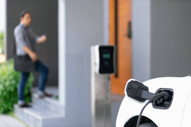istock Focus EV charging station at home with blur progressive man in background. 1463190880